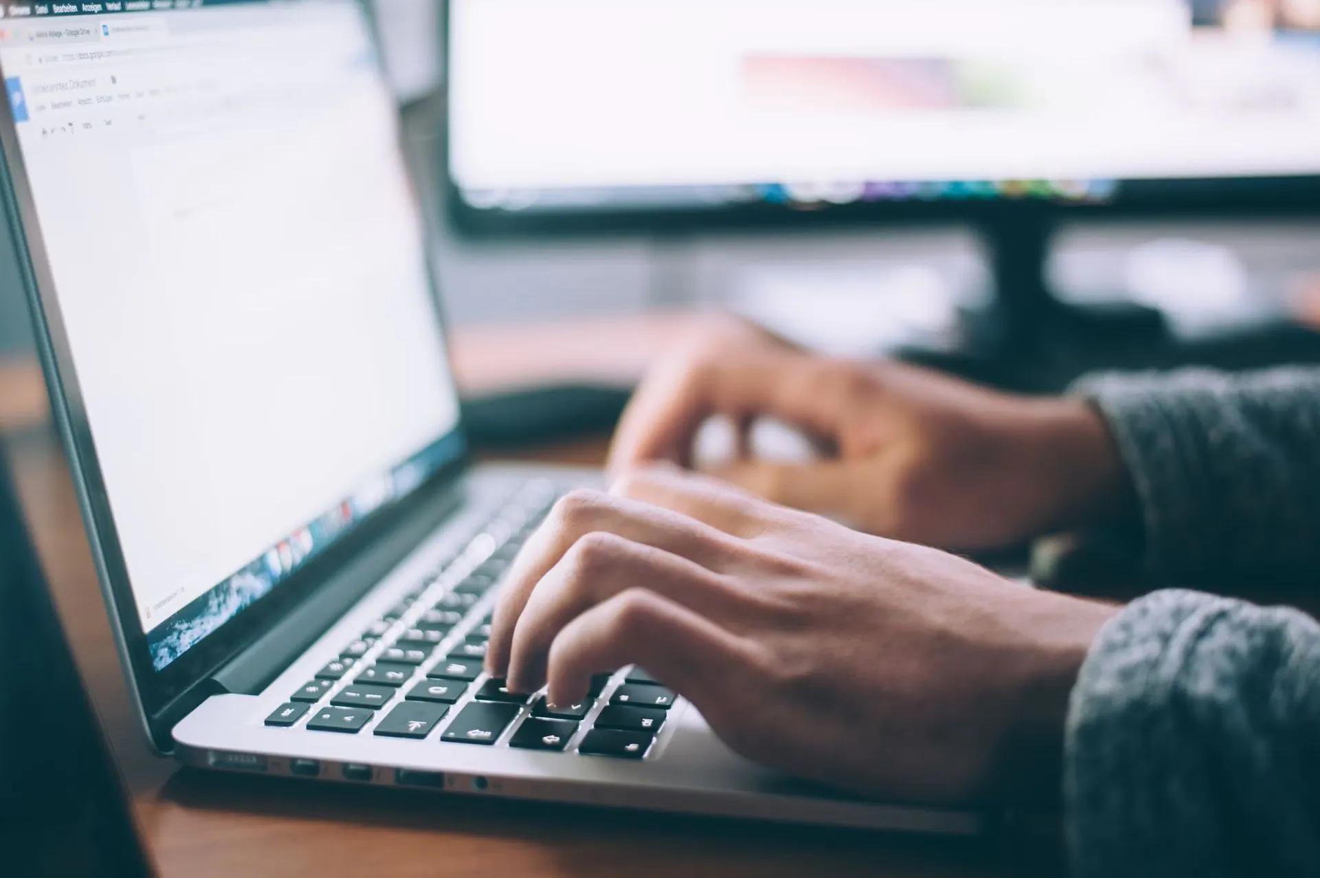 man aan het typen op laptop